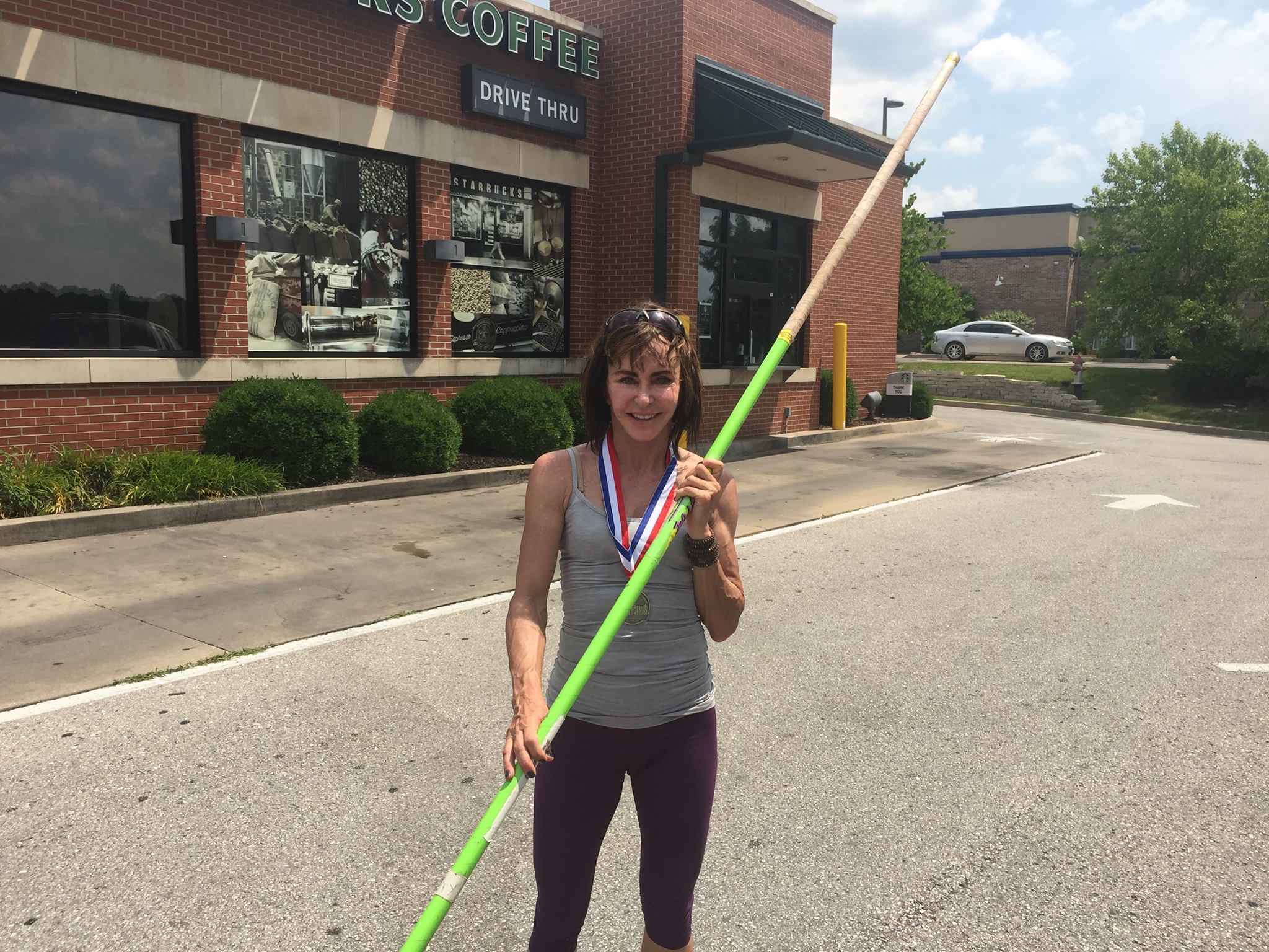 Kippy Hoene smiling with a pole-vaulting pole and a medal around her neck.
